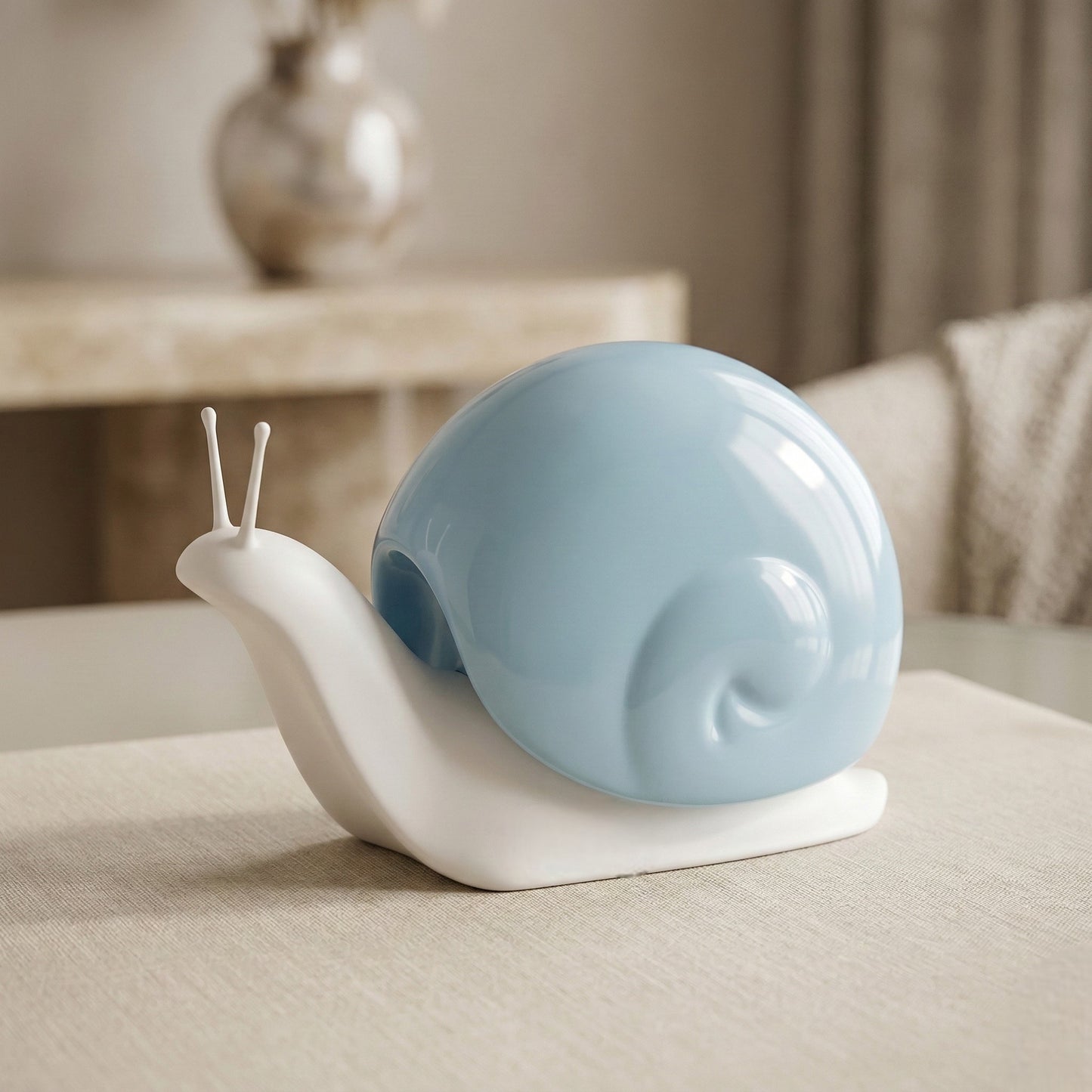 Decorative snail sculpture with a blue shell on a beige surface