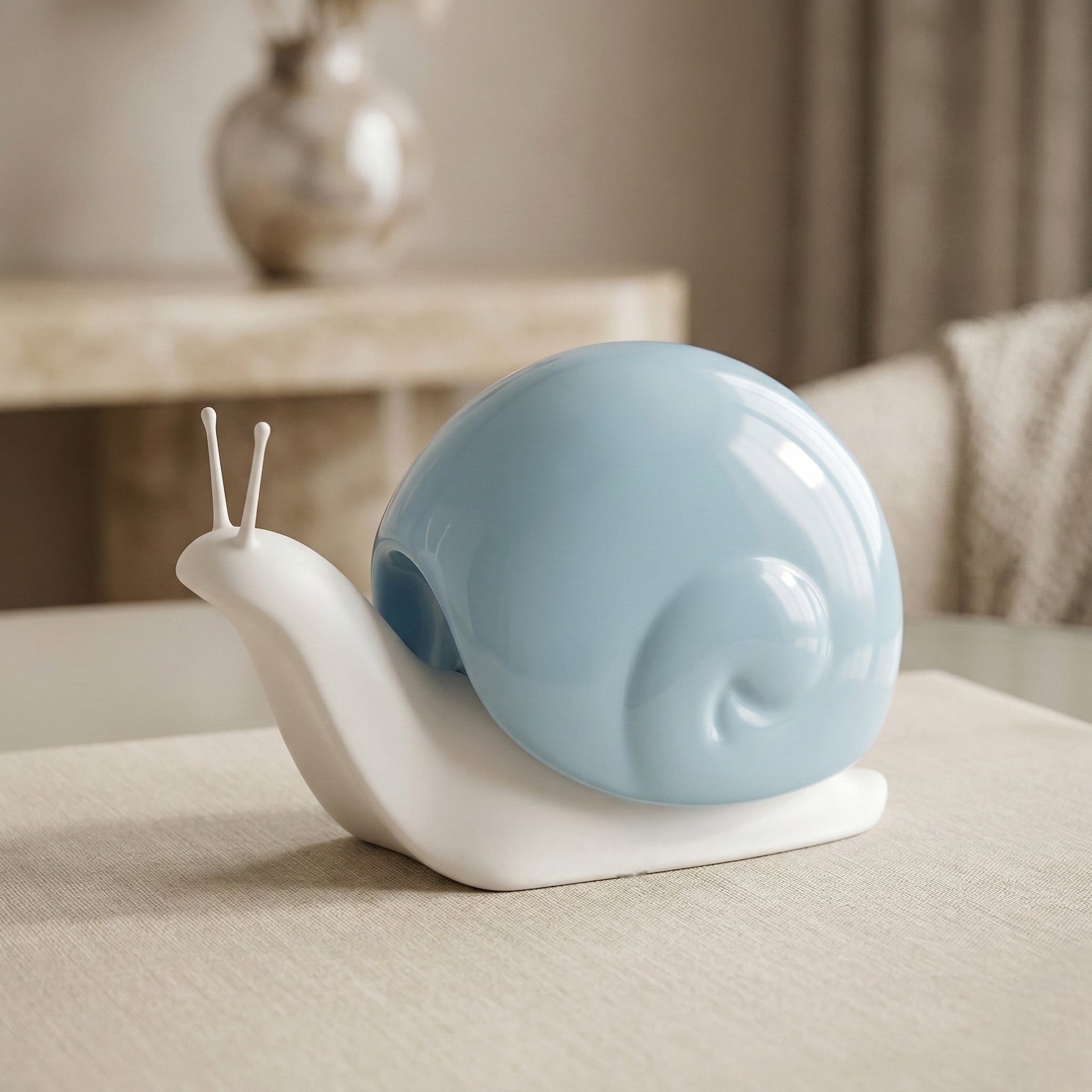 Decorative snail sculpture with a blue shell on a beige surface