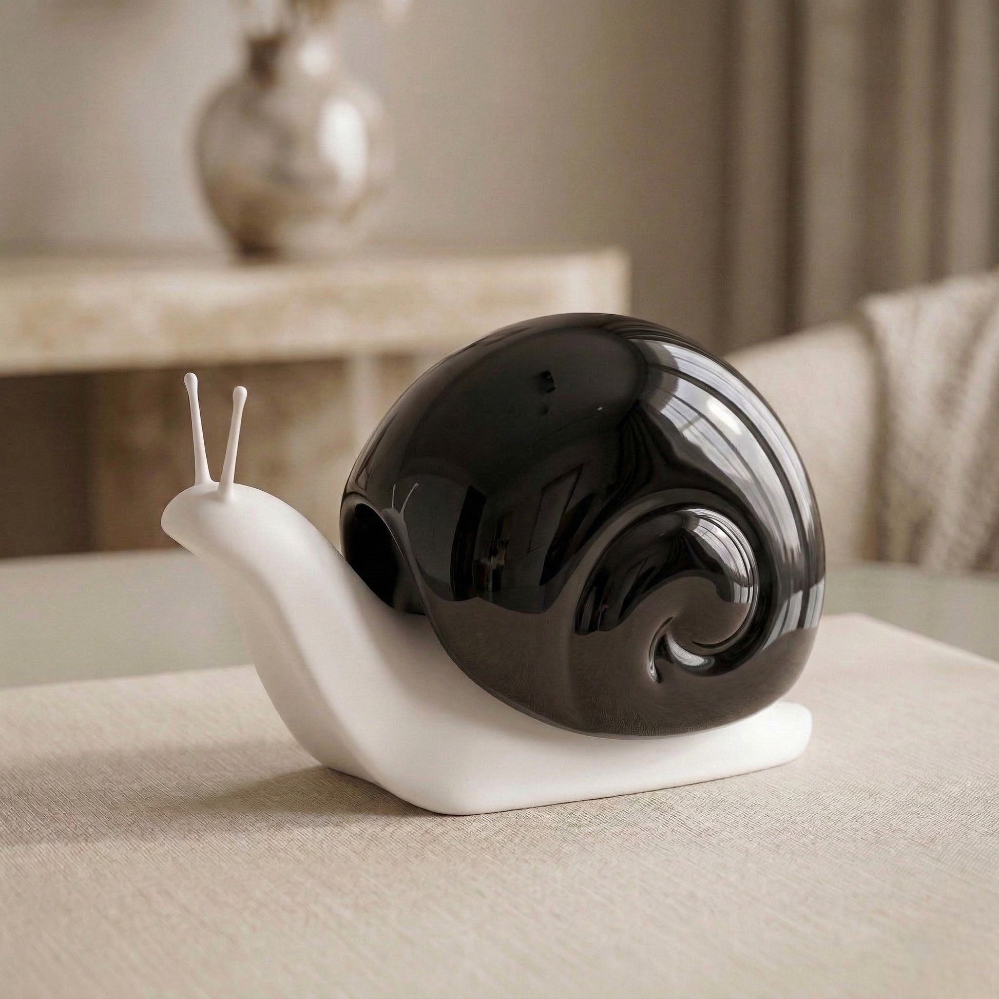 Decorative snail sculpture with black shell and white body on a surface.
