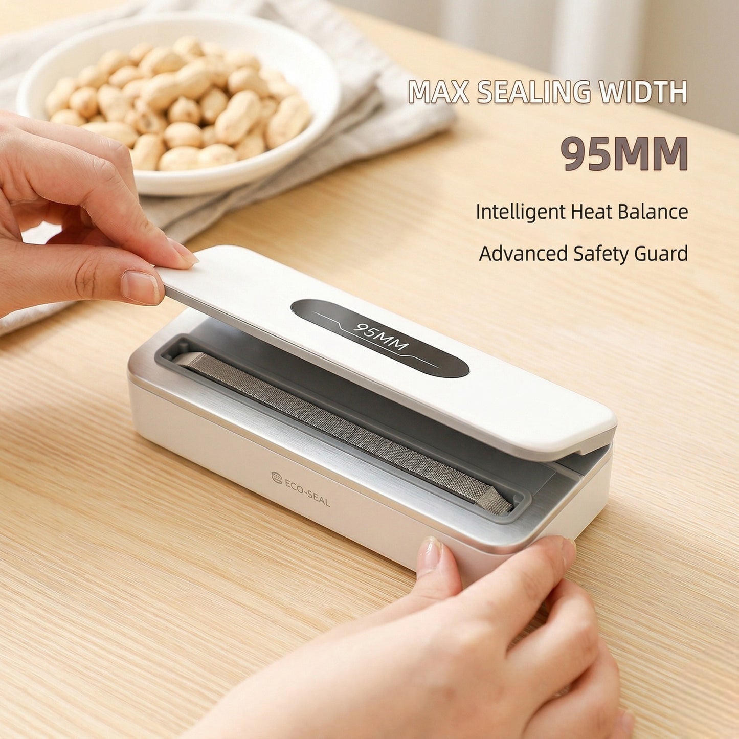 Hand using a food vacuum sealer on a wooden table with a bowl of peanuts in the background.