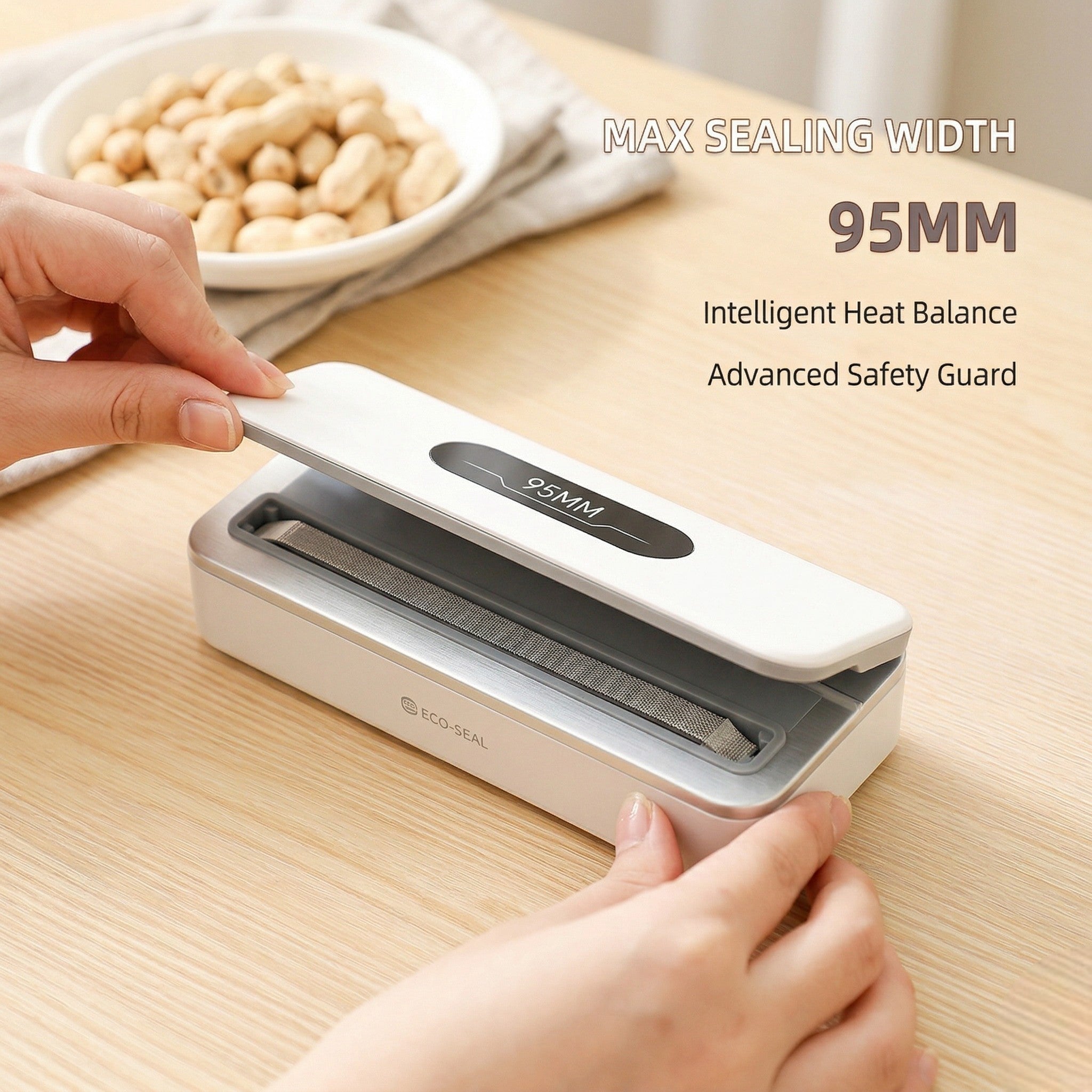 Hand using a food vacuum sealer on a wooden table with a bowl of peanuts in the background.