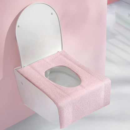 Pink toilet seat cover on a white toilet against a pink background