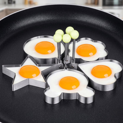 Egg-shaped metal molds on a frying pan with eggs cooked inside.