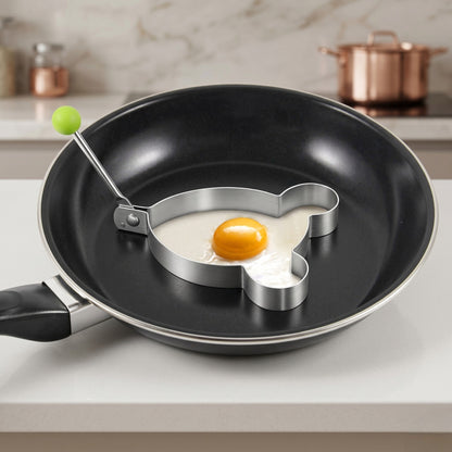 Frying pan with heart-shaped egg ring on a kitchen counter