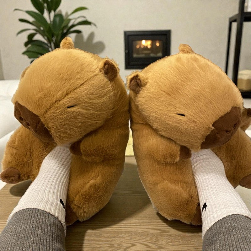 Two brown teddy bear slippers worn by a person sitting on a couch.