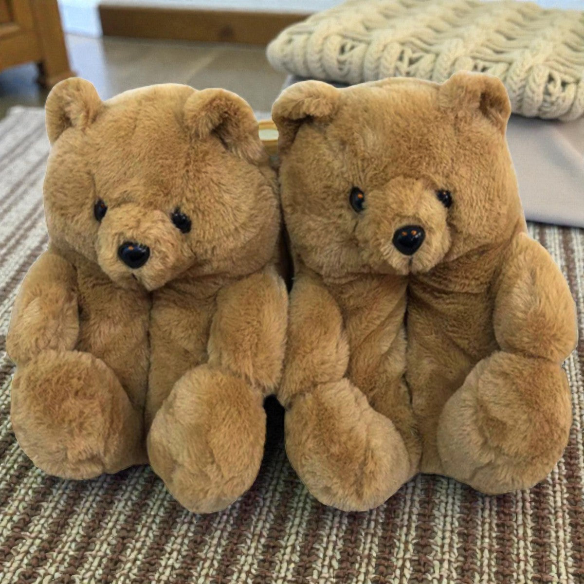 Two brown teddy bears slippers sitting on a textured surface.