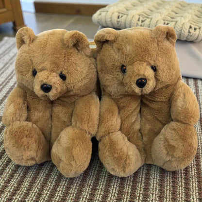 Two brown teddy bears slippers sitting on a textured surface.