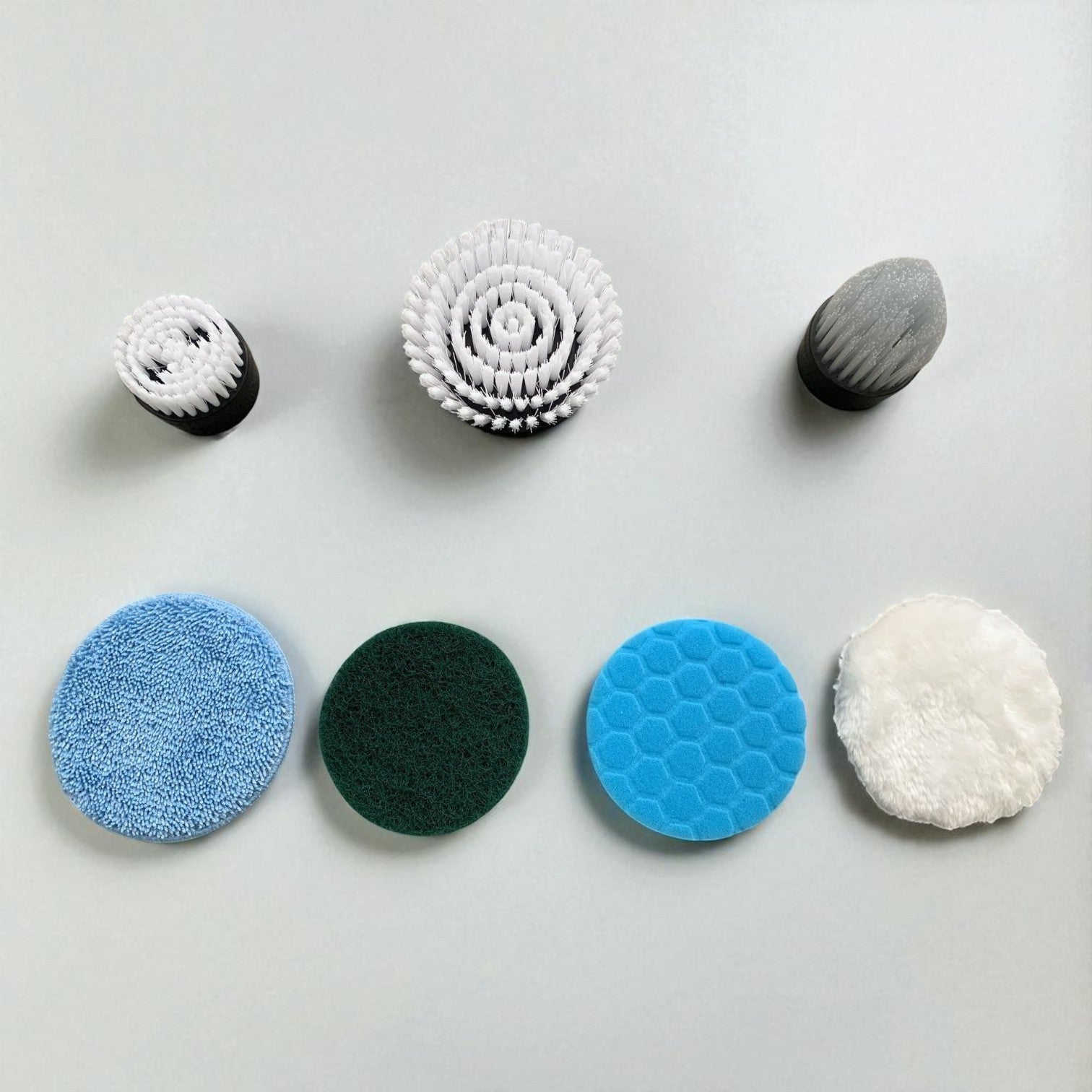 Set of various cleaning brushes and sponges on a light gray background