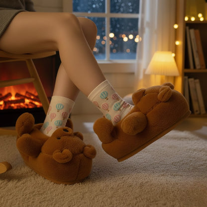 Person wearing brown bear slippers with a cozy indoor setting featuring a fireplace and books.