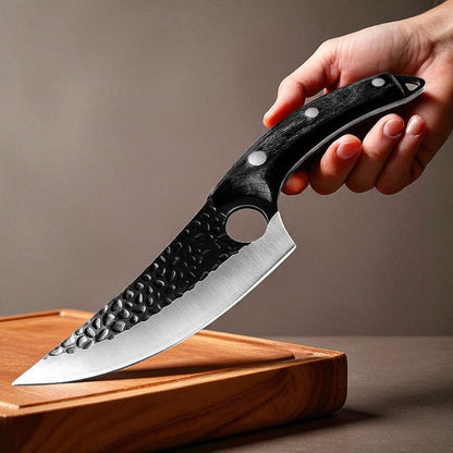 Hand holding a knife with a black handle on a wooden cutting board against a brown background
