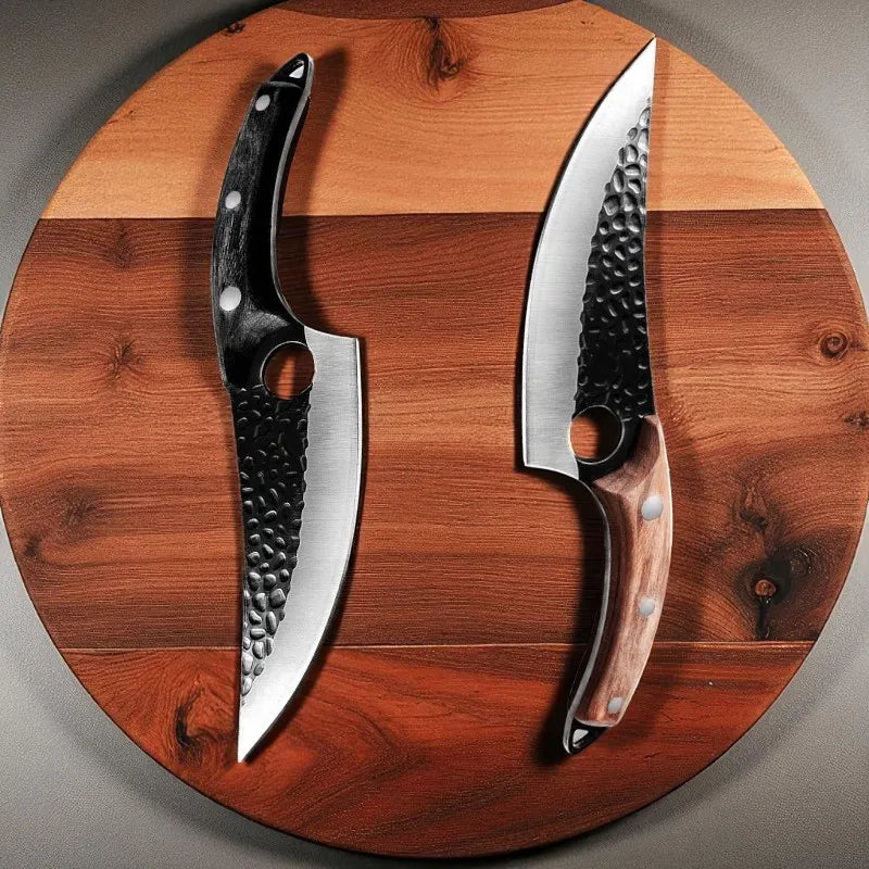 Two curved chef-style knives displayed side by side on a round wooden board. One knife has a black handle with silver rivets and a hammered blade, while the other has a brown wood-grain handle with silver rivets and a hammered blade.
