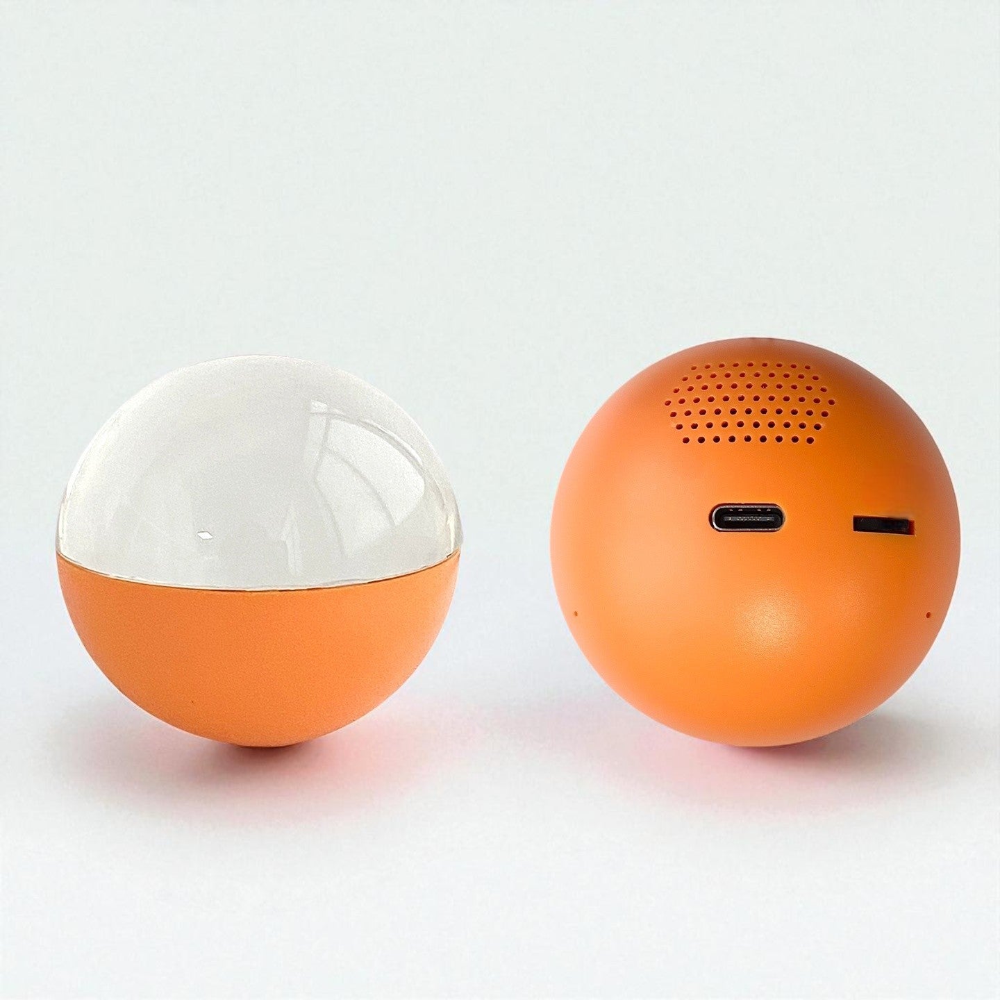 Two spherical orange video player ball with one having a white top on a light gray background
