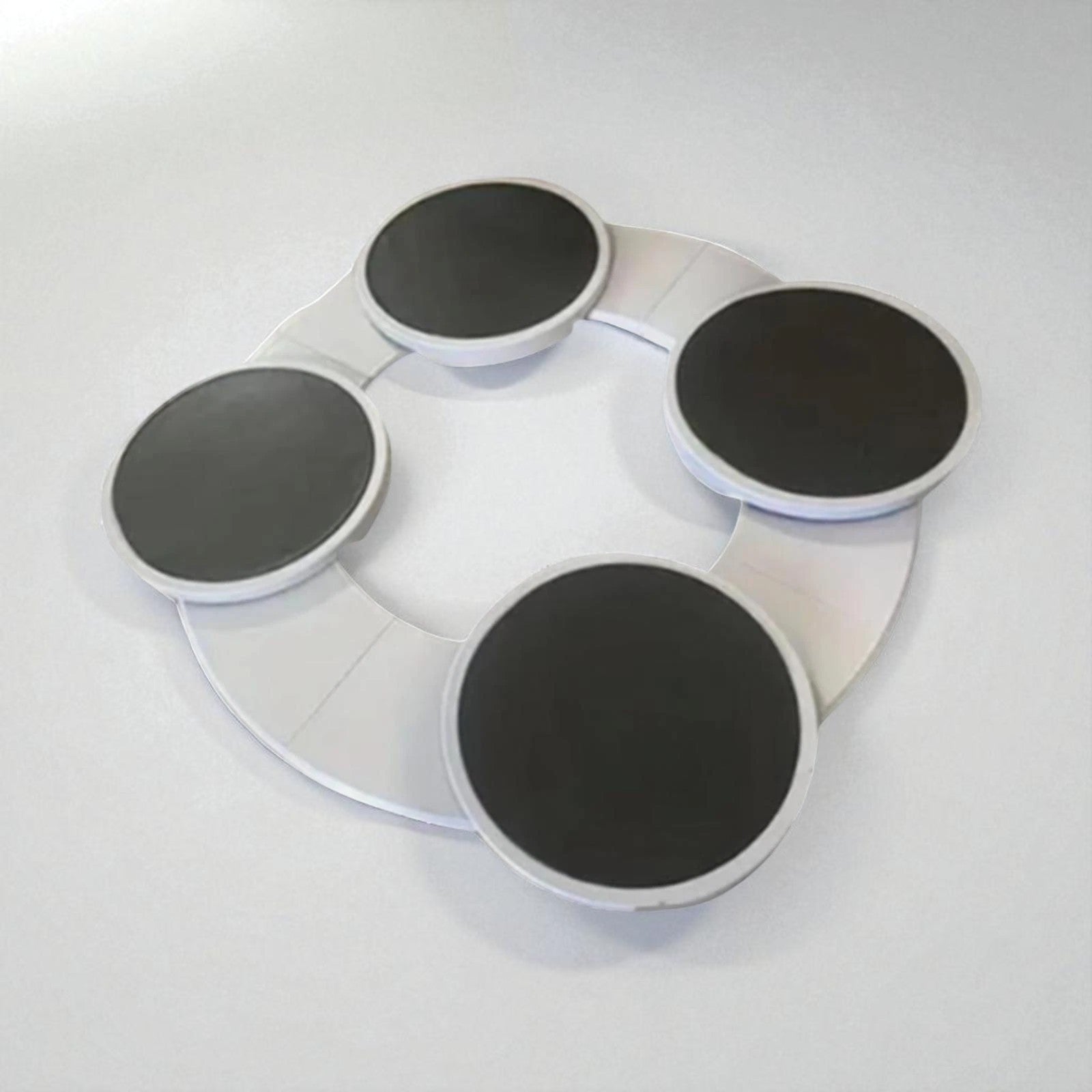 Round white tray with four black circular pads on a light gray background