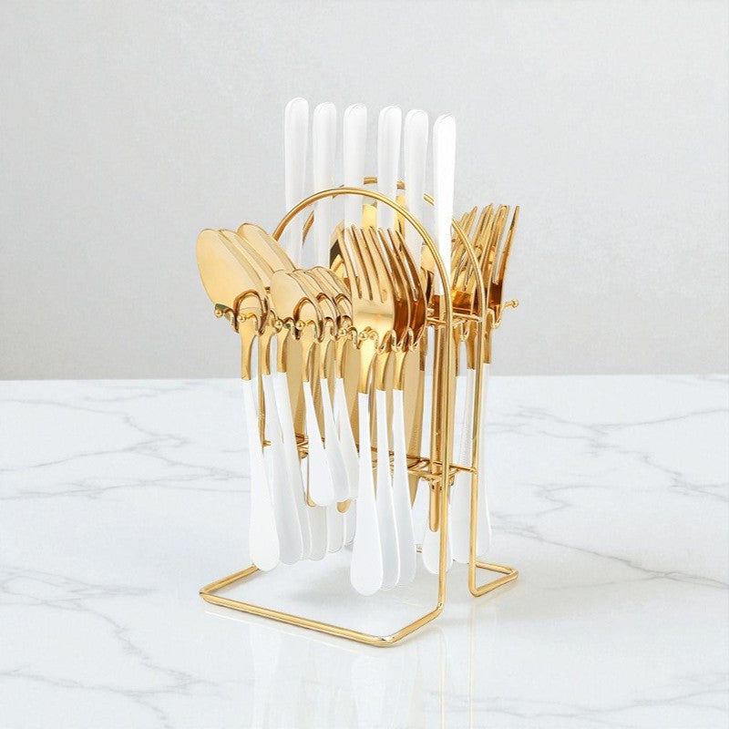 Gold cutlery holder with white utensils on a marble surface