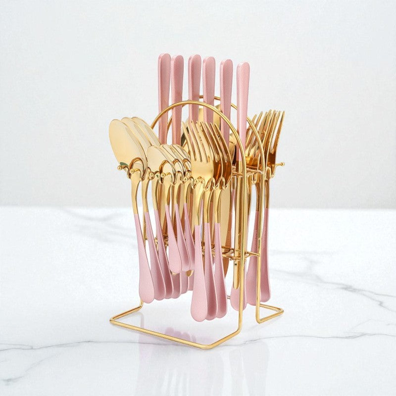 Gold and pink cutlery set in a stand on a white marble surface