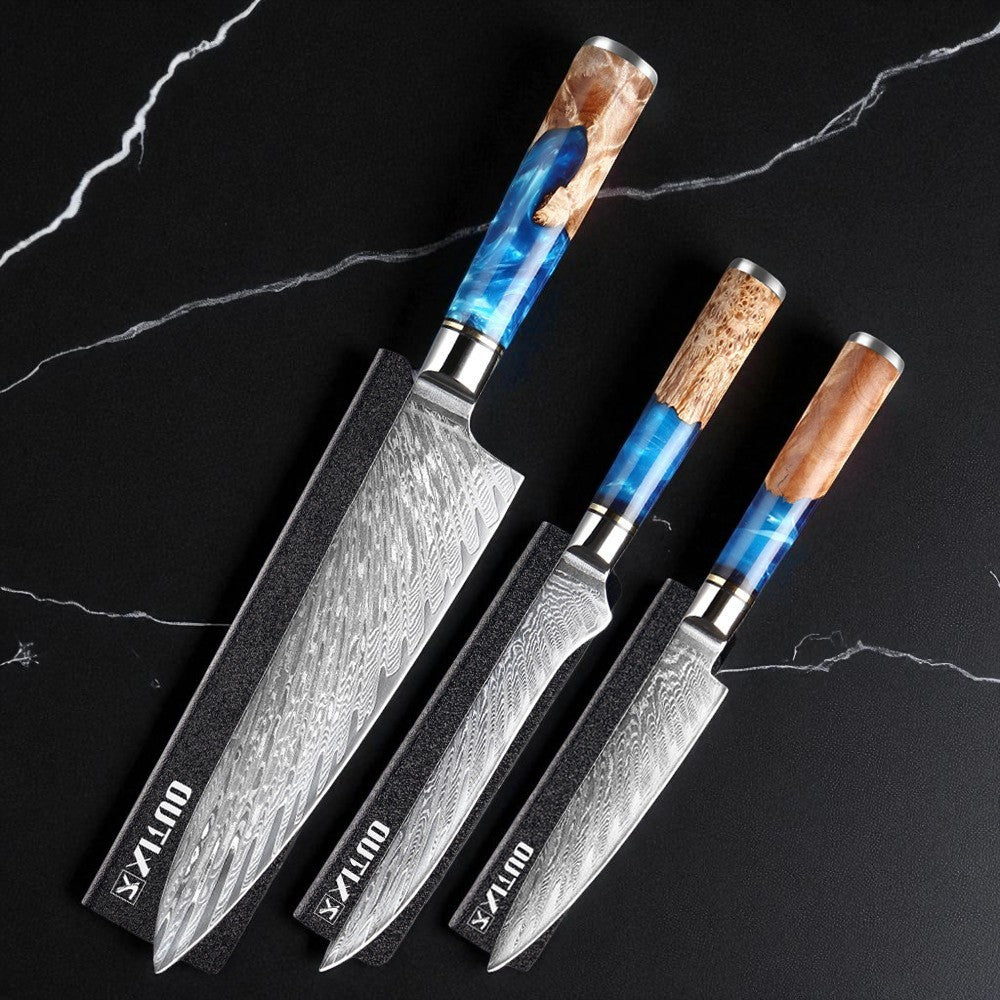 Three Damascus steel knives with wooden handles on a black marble surface